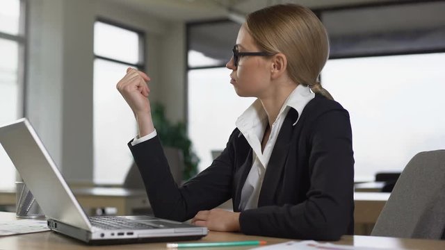 Woman looking at nails from boredom at work in office, lack of motivation