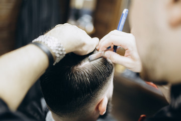 Man hairdresser cutting man's hair with straight razor