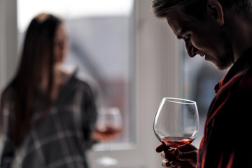 Young beautiful couple in plaid shirts on the balcony of a multistory building. Drink and taste wine, laugh and embrace.