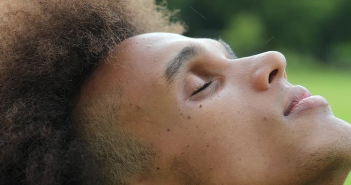 Young african man closing and opening eyes, looking up to sky with faith and hope