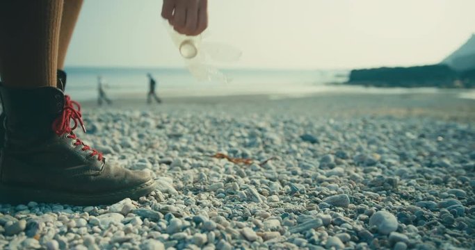 Woman cleaning up plastic waste on beach