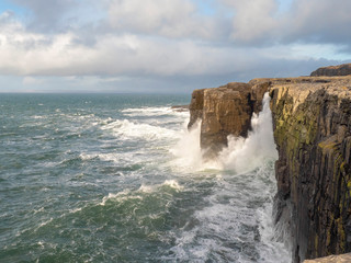 West of Ireland. Mini cliff, county clare, strong wave hits cliff, Sunny day. Atlantic ocean.