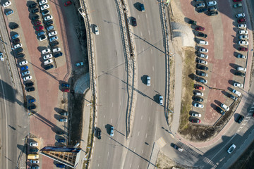 Aerial view of parking lot with parked cars and asphalt bridge road with traffic, top view from drone