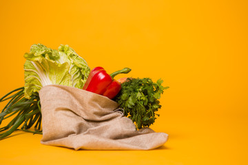 linen bag for vegetables, eco bag with vegetables,eco-friendly vegetable bag on yellow background, space for text