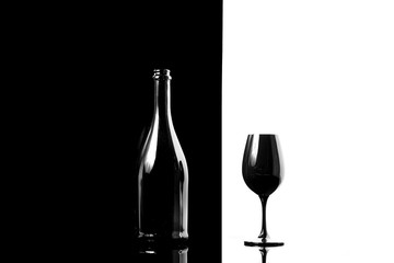Black champagne bottle with black champagne glass isolated on black and white background