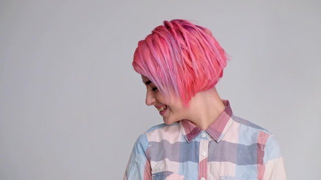 Young beautiful girl with a short hair cut pixie bob. Color hair coloring, red pink color. Shirt in a cellar, casual style, white background.