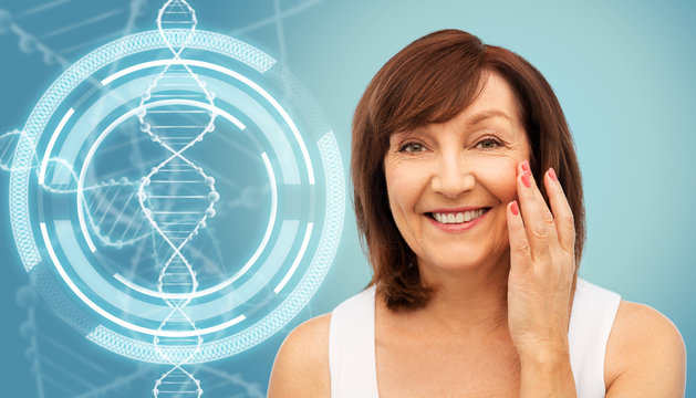 beauty, biotechnology and anti-age concept - portrait of smiling senior woman touching her face over blue background and dna molecule hologram - Powered by Adobe