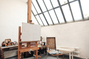 Bright art studio with a large window. Easels and canvases.