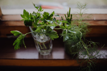 bunch of fresh parsley and dill weed in a glass on a windowsill