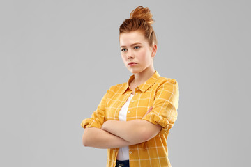 people concept - serious red haired teenage girl in checkered shirt with crossed arms over grey...
