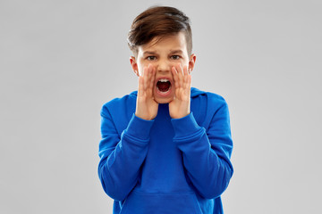 childhood, expressions and bullying concept - angry boy in blue hoodie shouting over grey background © Syda Productions