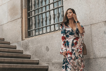 close up of a beautiful asian Philippine female in her 20s posing against a stone wall on stairs  showing her sexy face and soft skin with her elegant dress looking to her right off into the distance 