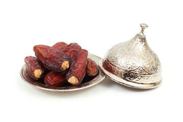 Islamic festival of Ramadan concept. with a delicious tropical dates on a silver plate and on white isolated background. Traditional Middle East culture. Ramadan Kareem.