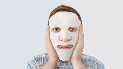  beautiful and cute guy  in mask, skin care and moisturizing, white background                                    