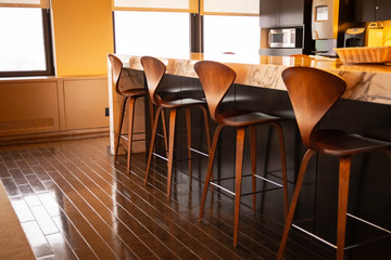 Fine wood chairs lined up at a spacious kitchen breakfast bar