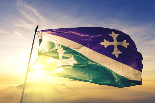 Adjuntas municipality of Puerto Rico flag waving on the top sunrise mist fog