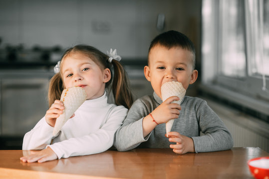 kids boy and girl eating ice cream cone in the kitchen is a lot of fun