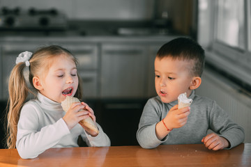 kids boy and girl eating ice cream cone in the kitchen is a lot of fun