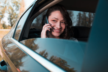 Beautiful successful businesswoman talk on her mobile phone in a backseat of a car