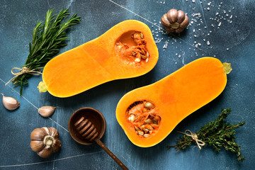 Halves of raw organic butternut squash with ingredients for making . Top view with copy space.
