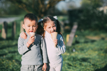 Obraz premium Kids Boy and girl eating ice cream outdoors on grass and trees background