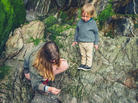 Mother and toddler exploring rocks on the beach