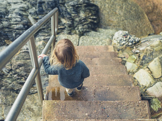 Fototapeta premium Little toddler going down some stairs on the coast