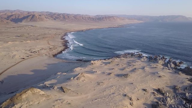 Las Tortolas beach aerial footage at Atacama Desert the sunset ray lights illuminate this amazing and idyllic beach in the middle of the desert, an arid awe landscape crashed by Pacific Ocean waters