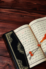 Islamic Holy Book Quran with rosary beads on wooden table background. Kuran the holy book os Muslims. Ramadan concept.