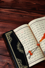 Obraz premium Islamic Holy Book Quran with rosary beads on wooden table background. Kuran the holy book os Muslims. Ramadan concept.