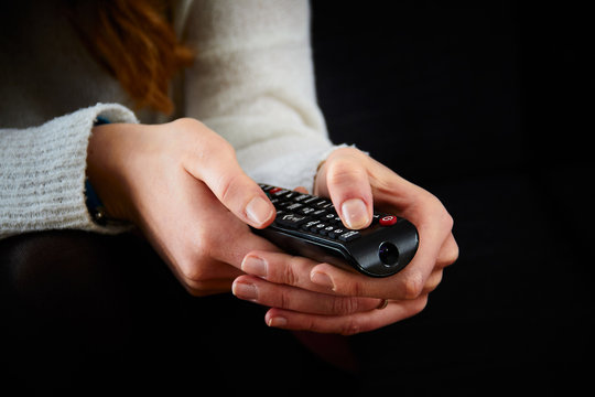 Close-up image of two female hands with remote control pointing forward