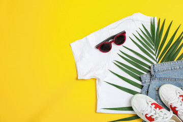 Flat lay composition with: women clothes and accessories, palm leaf on yellow background. Summer backdrop