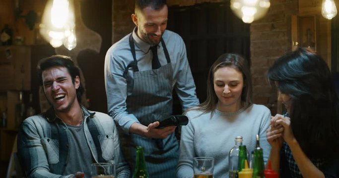 Slow motion of friends paying a bill after enjoying their meal  in a restaurant or pub. Shot in 8k.  Concept of restaurant and catering business, food and drink, POS, credit and debit card