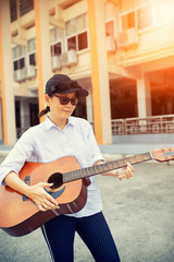 Fototapeta premium woman playing acoustic guitar on street side