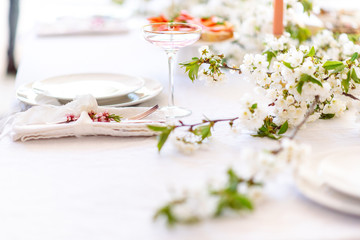 Laying and decor of the wedding banquet table. Plates, knives, forks, glasses, plates, flowers, snacks and fruit. The main thing in the details.