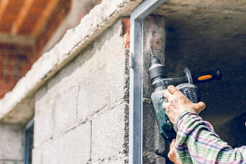 Fototapeta premium Construction industry worker using pneumatic hammer drill to cut the wall concrete brick drilling holes, close up