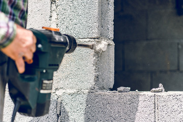 Construction industry worker using pneumatic hammer drill to cut the wall concrete brick, close up