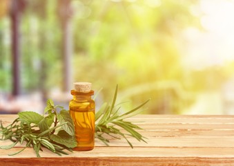 Oil bottle and green herbs on blue background