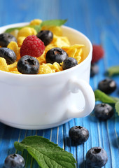 Healthy eating, food and diet concept - Cornflakes with berries raspberries and blueberries on blue wooden background.