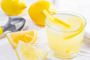 Summer drink of lemon, or lemonade, and hand juicer on white wooden table.