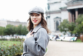 Outdoor photo of fashionable female model with hat walking around city in autumn vacation