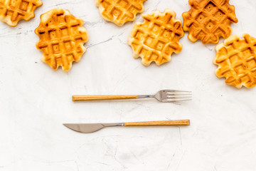 Fototapeta na wymiar Homemade Viennese waffles and fork with knife on white marble background top view