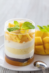 Sweet homemade Mango dessert, cheesecake, trifle, mouse in a glass jar on a light wooden...
