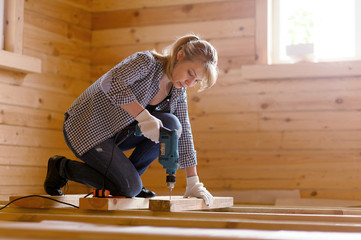 Young woman carpenter with drill