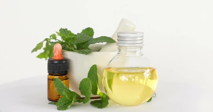 Aroma essential oil from peppermint in the bottle with fresh green mint leaf , rotation 4k dci