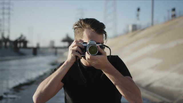 Photographer shoots on vintage film camera at Los Angeles river channels, interesting hobby, shooting film, old camera