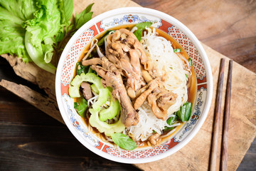 Rice noodles soup with stewed chicken wing and feet in a bowl with chopsticks