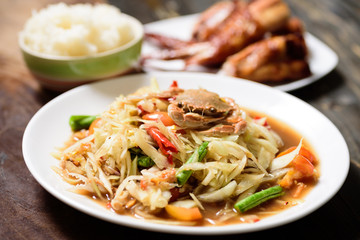Spicy green papaya salad,grilled chicken wing and sticky rice. Thai food (Som Tum)