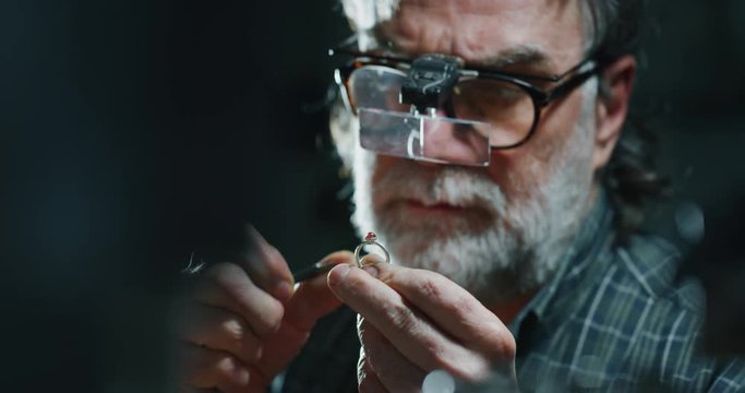 Slow motion of experienced goldsmith working on a handmade jewelry ring with precious diamond stones in a workshop. Shot in 8K. Concept of jewelry, luxury, goldsmith, diamonds, brilliance.
