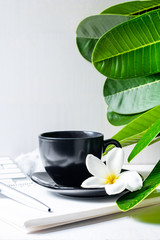 Coffee mug black with flower and leaves on  workspace